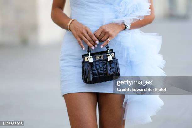 Tamara Kalinic wears a white tulle wrap / oversized embroidered asymmetric shoulder short tube dress, a black shiny leather embossed pattern handbag...