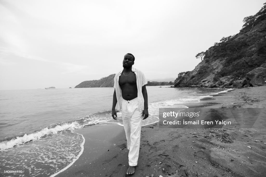Black man sunbathing in the sea on the beach reading a magazine