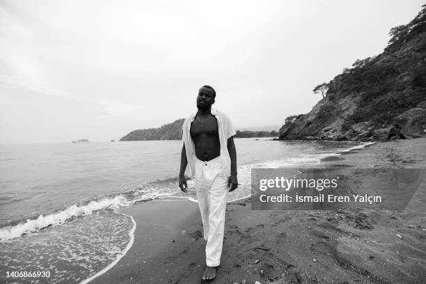black man sunbathing in the sea on the beach reading a magazine - national geographic society - fotografias e filmes do acervo