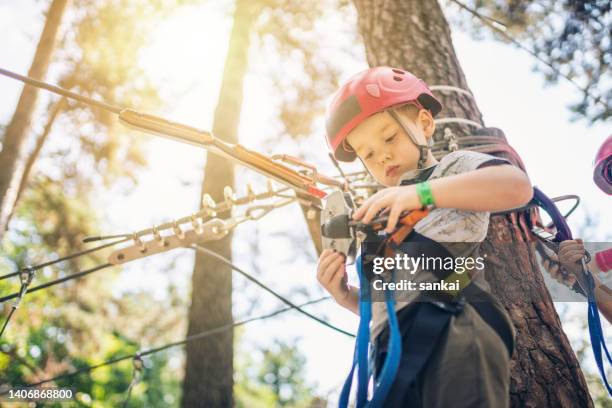 cute little boy goes through an obstacle course in an adventure park at sunset - safe kids day stock pictures, royalty-free photos & images