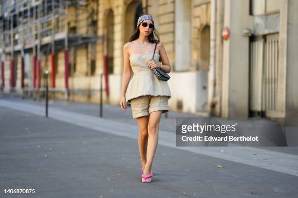 Gabriella Berdugo wears a blue and beige Dior Oblique Jacquard print pattern silk scarf from Dior, black sunglasses, gold chain pendant earrings, a...