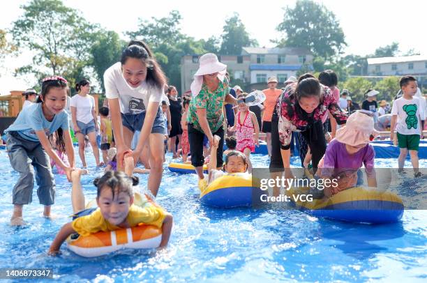 Children and their parents enjoy themselves in a water pool at a kindergarten on a hot summer day on July 5, 2022 in Huaying, Guang an City, Sichuan...