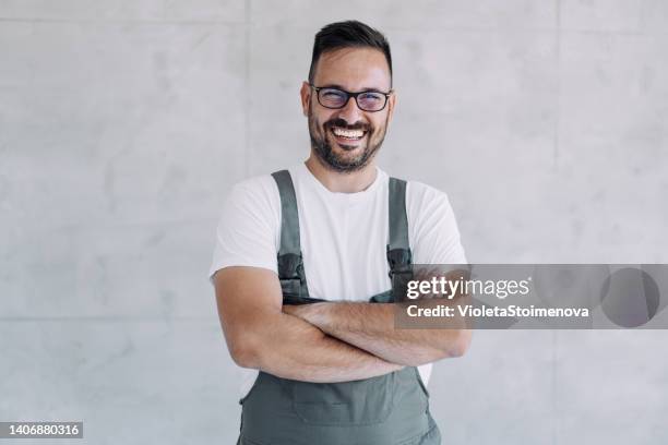 young male worker in an overall uniform posing at his workplace. - bib overalls 個照片及圖片檔