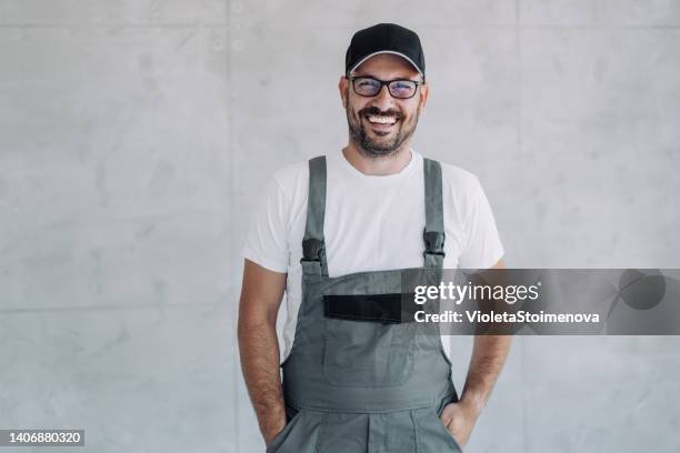 giovane lavoratore di sesso maschile in uniforme generale in posa sul posto di lavoro. - bib overalls foto e immagini stock