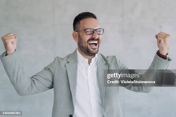 handsome young businessman celebrating his success. - business people cheering in office stockfoto's en -beelden