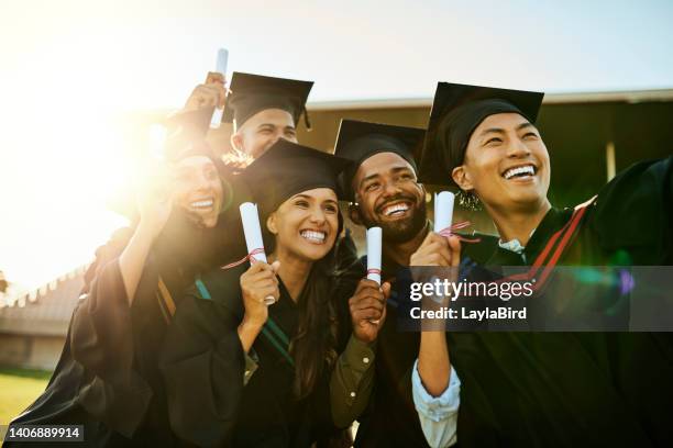 qualified students on graduation day. group of pupils in gowns taking a selfie with phone at ceremony. motivated graduates capturing memorable photos, celebrating academic achievement and milestone - graduates stockfoto's en -beelden
