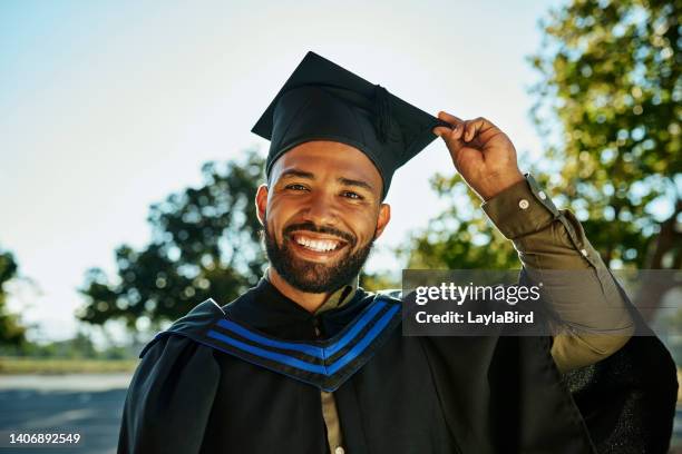 retrato de un graduado sonriente con bata y sombrero de pie solo en el campus universitario en la ceremonia de graduación. emocionado, feliz postgrado calificado graduado de la universidad para la licenciatura académica, maestría y grado - masters degree fotografías e imágenes de stock