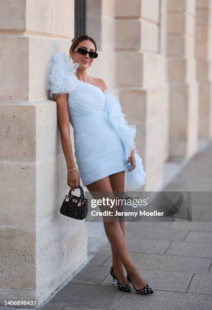 Tamara Kalinic seen wearing black sunglasses from Miu Miu, a gold diamond necklace, a white tulle wrap/oversized embroidered asymmetric shoulder...