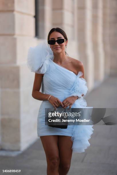 Tamara Kalinic seen wearing black sunglasses from Miu Miu, a gold diamond necklace, a white tulle wrap/oversized embroidered asymmetric shoulder...