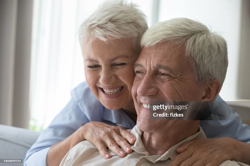 Closeup shot affectionate smiling aged wife embrace husband from behind
