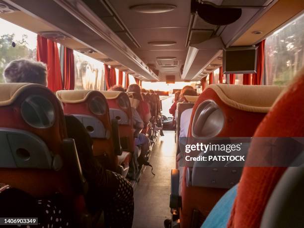 rear view of unrecognizable passengers traveling on a coach bus at sunset. - coach bus stock pictures, royalty-free photos & images