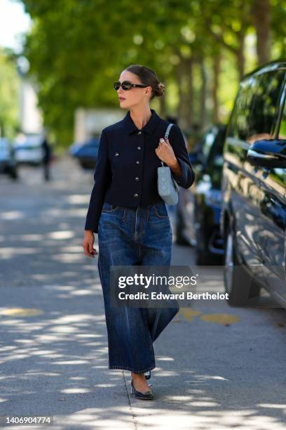 Sophia Roe wears black sunglasses, a navy blue buttoned jacket, navy blue large wide legs pants, a blue matte leather Lady D-Lite hand bag from Dior,...