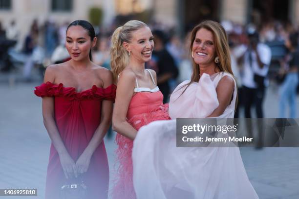 Korlan Madi seen wearing a red ruffled off-shoulder long dress and a red leather Giambattista Valli bag; Leonie Hanne wears gold diamond earrings, a...