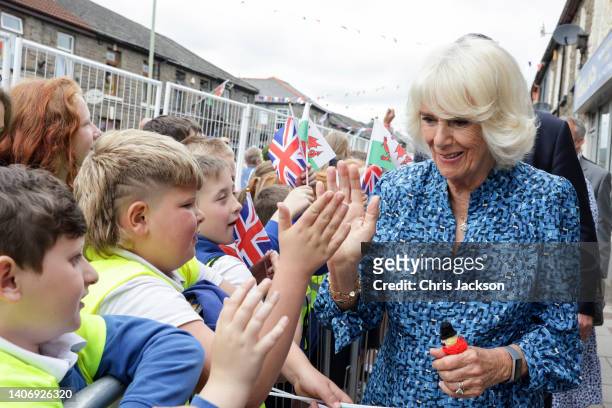 Camilla, Duchess of Cornwall high fives children during a visit to Treorchy High Street on July 05, 2022 in Rhondda, Wales. Eighty percent of the...