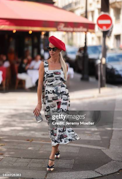 Denisa Palsha seen wearing black sunglasses from Burberry, a red beret, a white pattern midi dress from Ferrari, a silver leather belt, a silver...