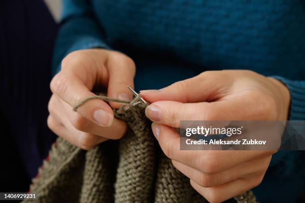 the girl is holding knitting and metal knitting needles in close-up. a freelance woman knits a wool sweater or clothes at home. the concept of hobbies, creativity, needlework, handmade. do what you love. home life, a break from household chores. - elastisch weefsel stockfoto's en -beelden