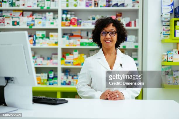 farmacéutico maduro en el mostrador sonriendo - farmacia fotografías e imágenes de stock