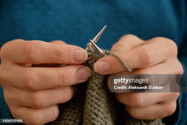 the girl is holding knitting and metal knitting needles in close-up. a freelance woman knits a wool sweater or clothes at home. the concept of hobbies, creativity, needlework, handmade. do what you love. home life, a break from household chores. - elastisch weefsel stockfoto's en -beelden