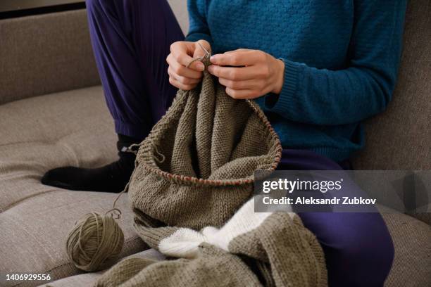 the girl is holding knitting and metal knitting needles in close-up. a freelance woman knits a wool sweater or clothes at home. the concept of hobbies, creativity, needlework, handmade. do what you love. home life, a break from household chores. - elastisch weefsel stockfoto's en -beelden