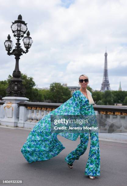 Denisa Palsha seen wearing black sunglasses from Dior, a blue flower pattern cape jumpsuit from Richard Quinn and black/gold leather Chanel high...