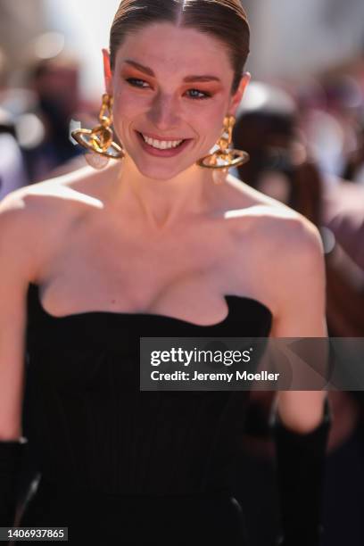 Hunter Schafer seen wearing gold pendant earrings, a black off-shoulder corset top and black long velvet gloves, outside the Schiaparelli show,...