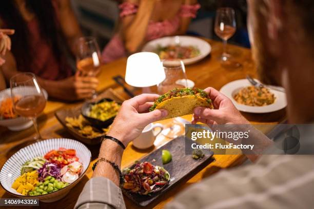 high angle view of unrecognizable man eating tacos, during dinner - mexican food stock pictures, royalty-free photos & images