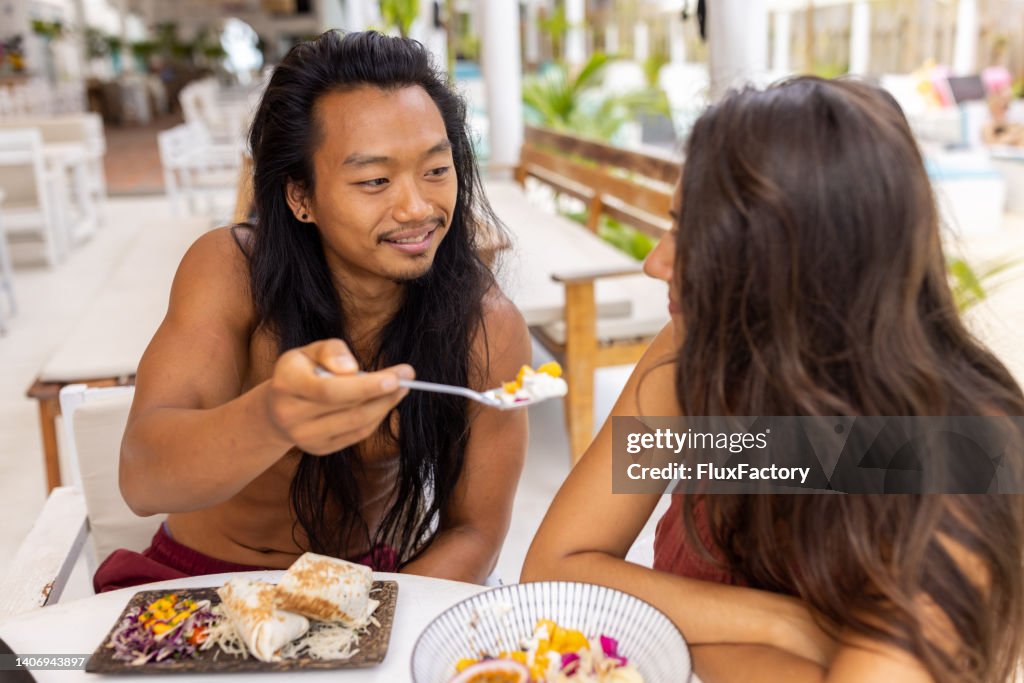 Man feeding his girlfriend during breakfast at the beach restaurant