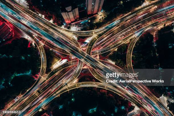 drone point view of overpass and city traffic at night - finance and economy stock pictures, royalty-free photos & images