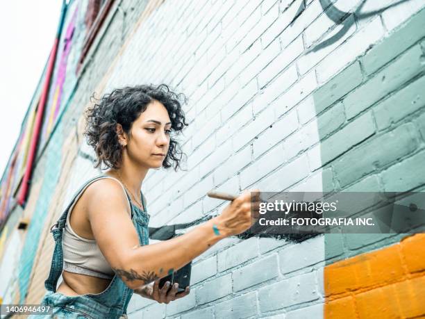 female artist painting large wall mural - wall painting stock pictures, royalty-free photos & images