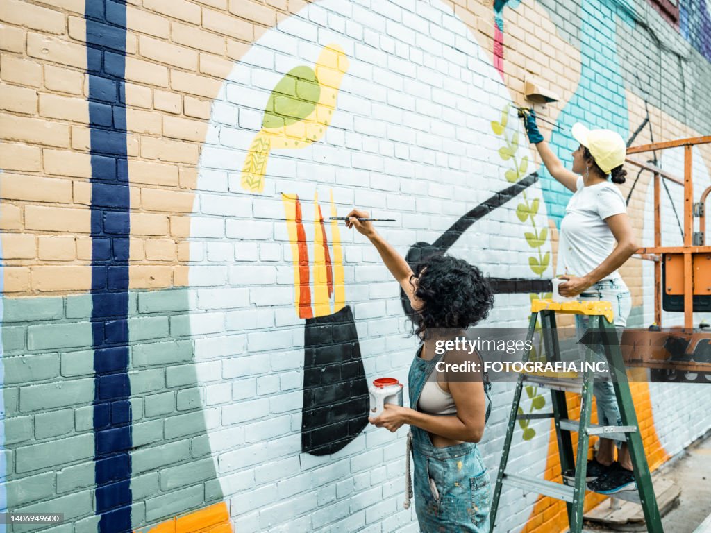 Two Female artists painting large wall mural