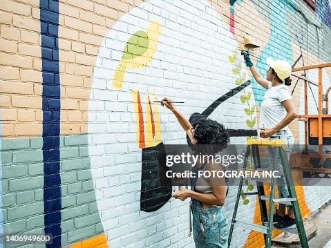 Two Female artists painting large wall mural Two Female artists painting large wall mural