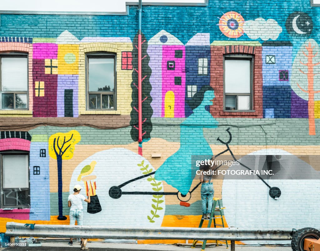 Female artist painting large wall mural