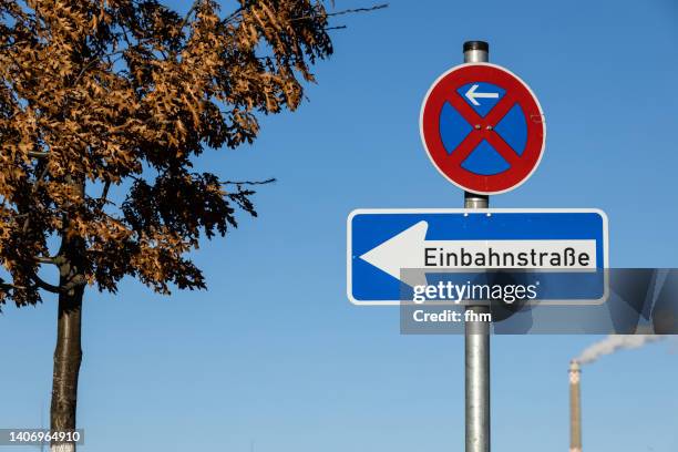 street signs "one way street" and "parking forbidden" with chimney in the background - einbahnstraßenschild stock-fotos und bilder