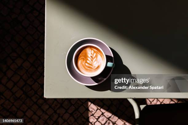 cup of cappuccino with latte art on the table, directly above view - cofee stock-fotos und bilder