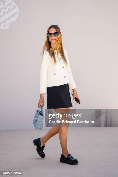 Charlotte Groeneveld wears black sunglasses, a white latte buttoned jacket from Dior, a black short skirt from Dior, a blue gray shiny leather Lady...
