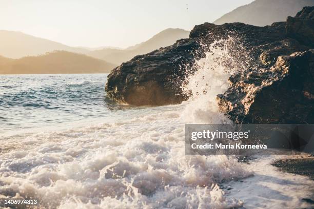 wave crashes against rocks on the beach. - waves crashing on rocks stock pictures, royalty-free photos & images