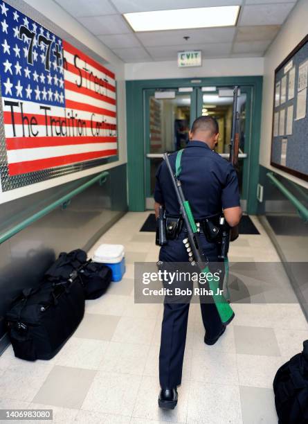 Los Angeles Police Department officer deploys for patrol duty carrying a 'less-lethal shotgun' after roll-call at 77th Street Division station,...