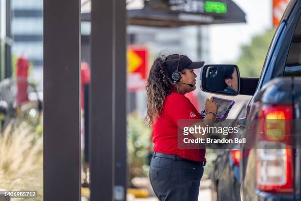 Chick-fil-A employee assists a customer in a drive-thru line on July 05, 2022 in Houston, Texas. According to an annual survey produced by the...