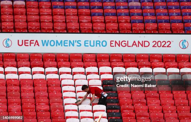 Member of staff cleans stadium seats during the UEFA Women's Euro England 2022 England Press Conference And Training Session at Old Trafford on July...