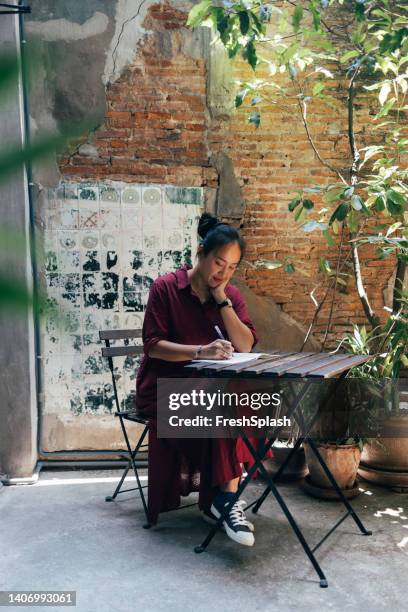 un étudiant souriant assis au café et étudiant - réfléchir écrire adulte 40 ans papiers photos et images de collection