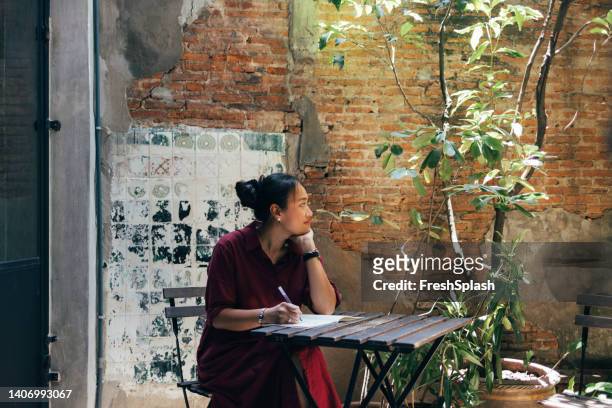 a smiling woman sitting at the cafe and studying - optimistic inspiring movement stock pictures, royalty-free photos & images