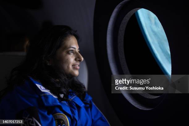 a commercial space traveler looking at the earth throughout  the window at inside of the spaceship. - space tourism stockfoto's en -beelden