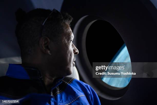 a commercial space traveler looking at the earth throughout the window at inside of the spaceship. - véhicule spatial photos et images de collection