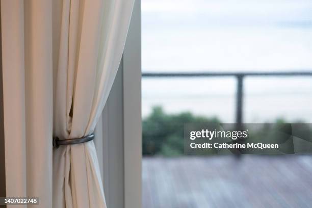pulled back white curtain panel reveals view from beachfront home - open window frame stock pictures, royalty-free photos & images