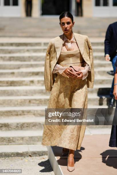 Alessandra de Osma wears a beige silk shirt, a beige ribbed shoulder-off top / flower print pattern long dress from Dior, a beige blazer jacket, a...