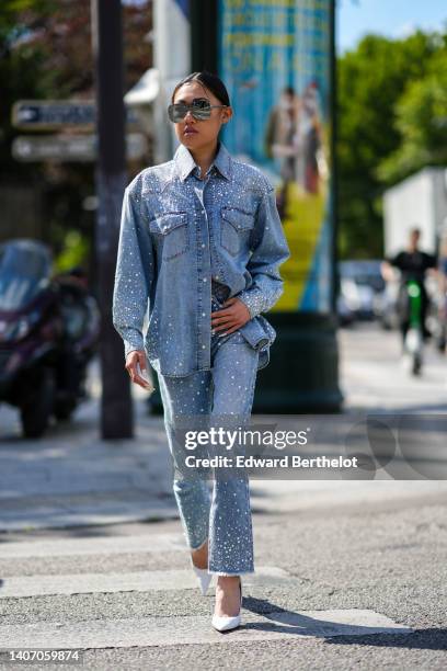 Jaime Xie wears gray sunglasses, a blue denim with embroidered rhinestones oversized shirt, blue denim with embroidered sequined cigarette pants,...