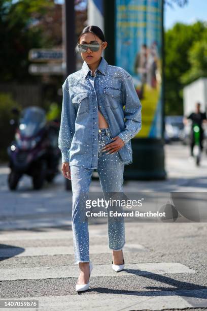Jaime Xie wears gray sunglasses, a blue denim with embroidered rhinestones oversized shirt, blue denim with embroidered sequined cigarette pants,...