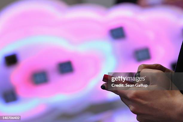 Visitor tries out a Microsoft-driven Nokia smartphone next to a symbol of a cloud at the Deutsche Telekom stand the day before the CeBIT 2012...