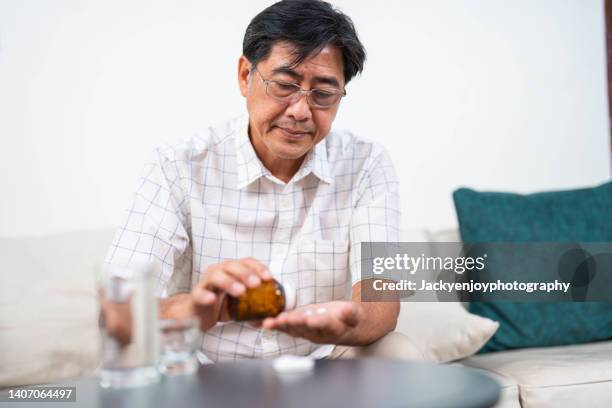 asian senior man holding daily pill box with pills - hand holding several pills photos et images de collection