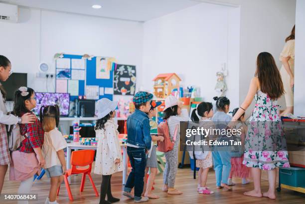 asian montessori preschool teacher guiding and arranging students waiting in line entering classroom in the morning - pessoas em fila imagens e fotografias de stock